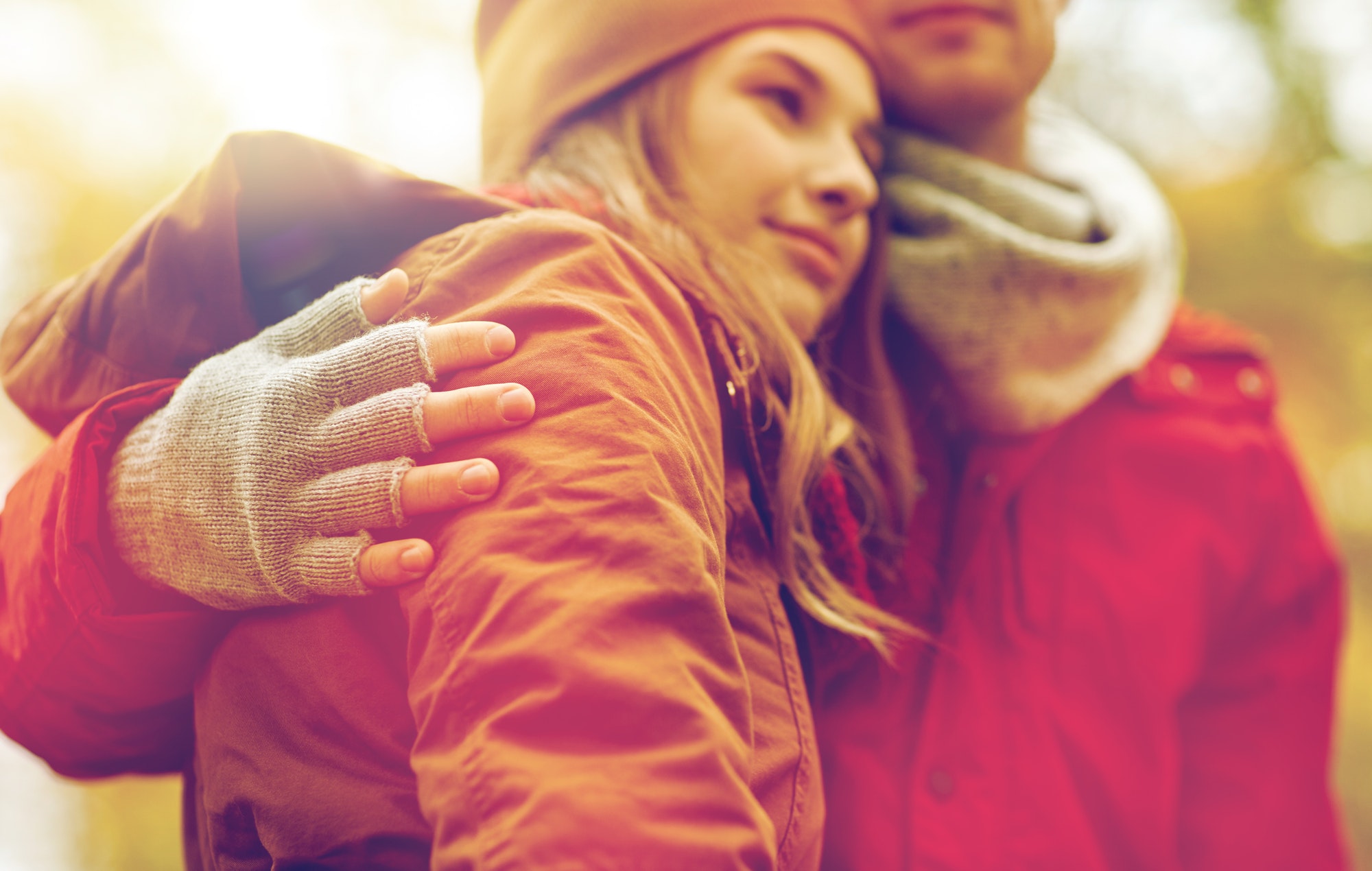 close up of happy couple hugging in autumn park